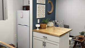A compact kitchen with a white refrigerator, wooden countertop, and a blue accent wall.