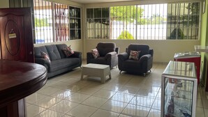 A living room with a sofa, armchairs, a coffee table, and a glass display case.