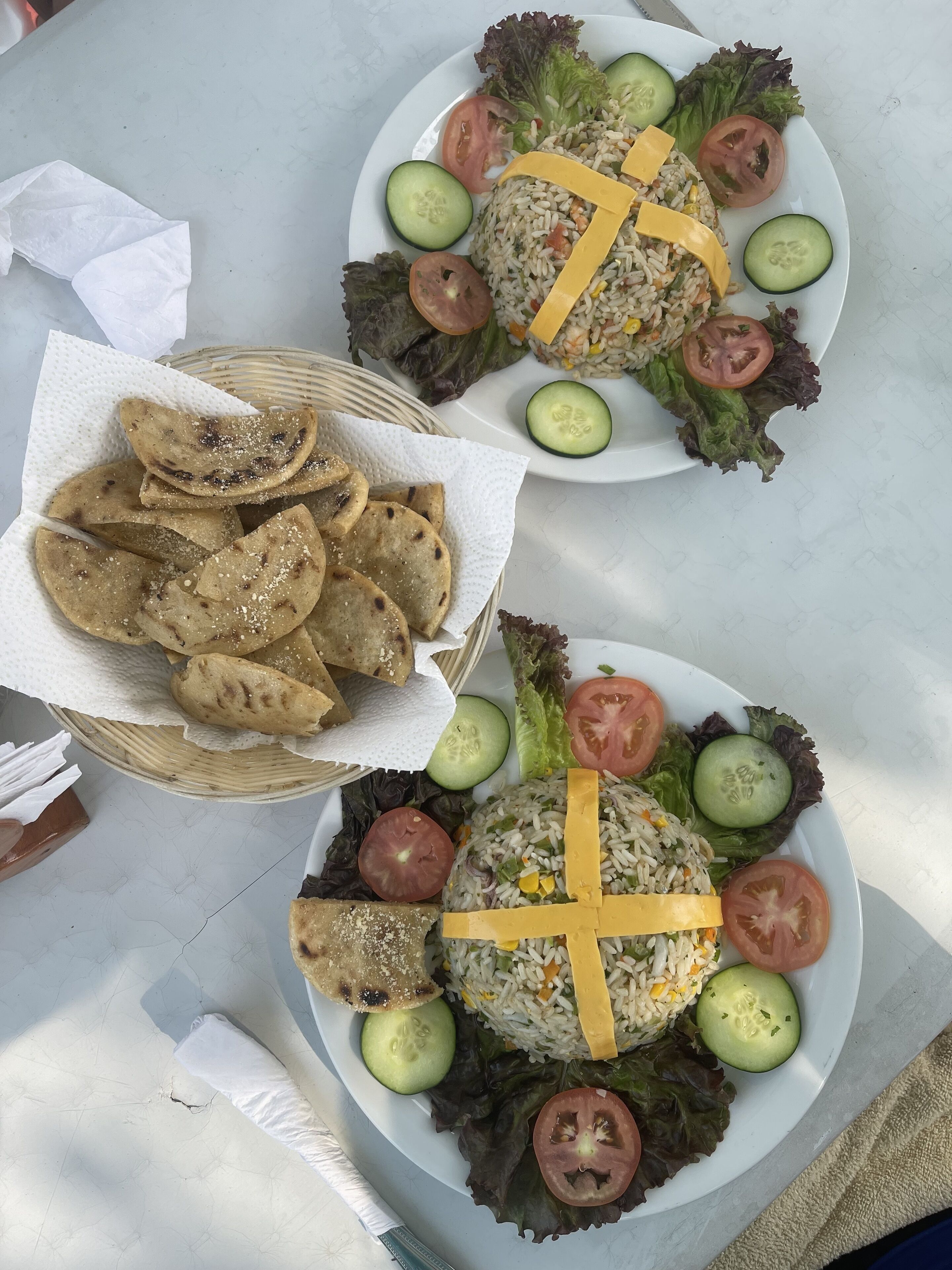 Dos platos de comida con arroz, verduras y panes planos sobre una mesa.