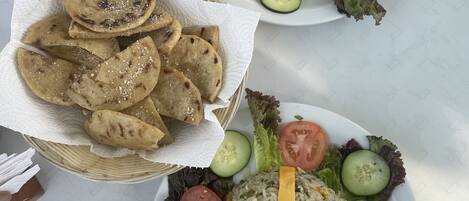 Dos platos de comida con arroz, verduras y panes planos sobre una mesa.