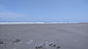 Privéstrand vlakbij, zwart zand, ligstoelen, parasols