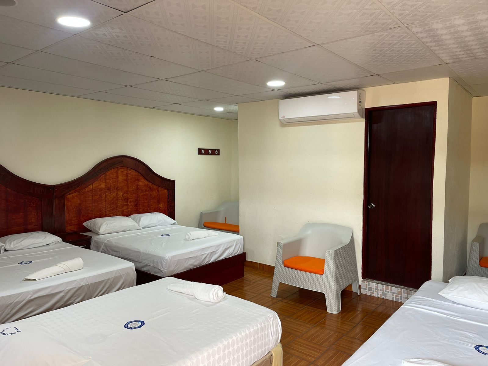Une chambre d’hôtel avec deux lits, une chaise, un appareil de climatisation et une porte.