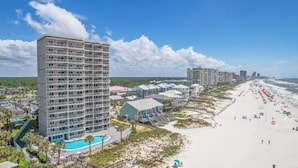 Un hôtel de grande hauteur doté de nombreux balcons, d’une piscine et situé en bord de mer.