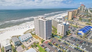 Un hôtel situé sur la côte, composé de plusieurs immeubles de grande hauteur, avec une plage et un parking.
