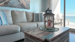 A living room with a sofa, a small table with a lantern, and a view of the outdoors.