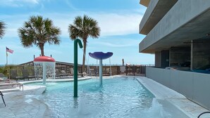 A swimming pool with water features, palm trees, and lounge chairs.