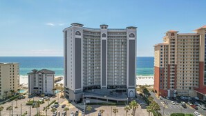 A high-rise hotel with multiple floors, a central courtyard, and a view of the beach.