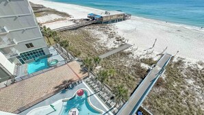A resort with a pool area, beach access, and a building with a view of the ocean.