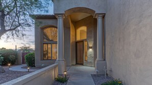 A modern building with a central entrance flanked by columns, a covered walkway, and a landscaped area with small plants and a pathway. - LUX Near Golf & Trails: Pvt POOL/Spa, Wood FP, Game Tables, TVs All BRs, EV Charger (Mesa)