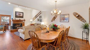 A spacious living room with a fireplace, a dining area with a wooden table and chairs, and a cozy seating area with a sofa and a chair.