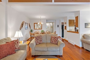 A living room with a sofa, a coffee table, and a dining area with chairs and a table.
