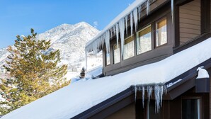 A building with icicles hanging from the roof, surrounded by snow-covered mountains.