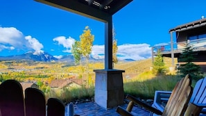 A covered outdoor seating area with a view of a mountain range and a town in the background. - Custom Home, Incredible Mountain Views, Private Hot Tub, Pool Table, Available for Monthly Rental (Silverthorne)