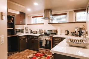 A compact kitchen with a stove, oven, microwave, and a coffee maker.