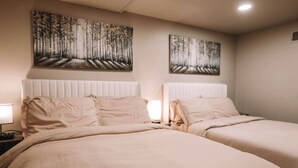 Une chambre d’hôtel avec deux lits, une table de chevet avec une lampe et deux tableaux au mur.