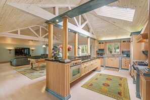 A spacious kitchen with wooden beams, a central island, and a dining area with a pool table. - Pure Serenity On Lake Rosseau (Windermere)