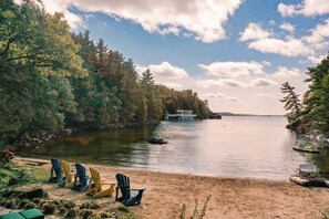 A lakeside view with chairs and a boat docked near the shore. - Pure Serenity On Lake Rosseau (Windermere)