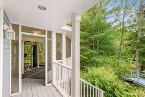 Une véranda couverte offrant une vue sur une salle de sport et une zone boisée naturelle.