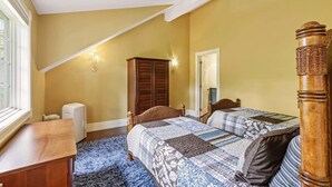 Quarto com duas camas, um guarda-roupa de madeira, um radiador e uma janela.