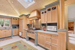 Una cocina amplia con armarios de madera, estufa a gas y microondas.