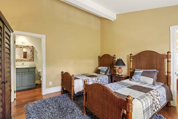 Une chambre à coucher avec deux lits en bois, une table de chevet avec une lampe, un miroir et un tapis bleu.