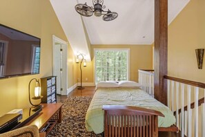 Een slaapkamer met een bed, een bureau, een stoel, een lamp, een spiegel en een raam.