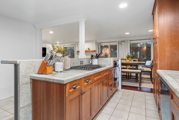 A modern kitchen with wooden cabinets, a central island, and a dining area with a table and chairs.