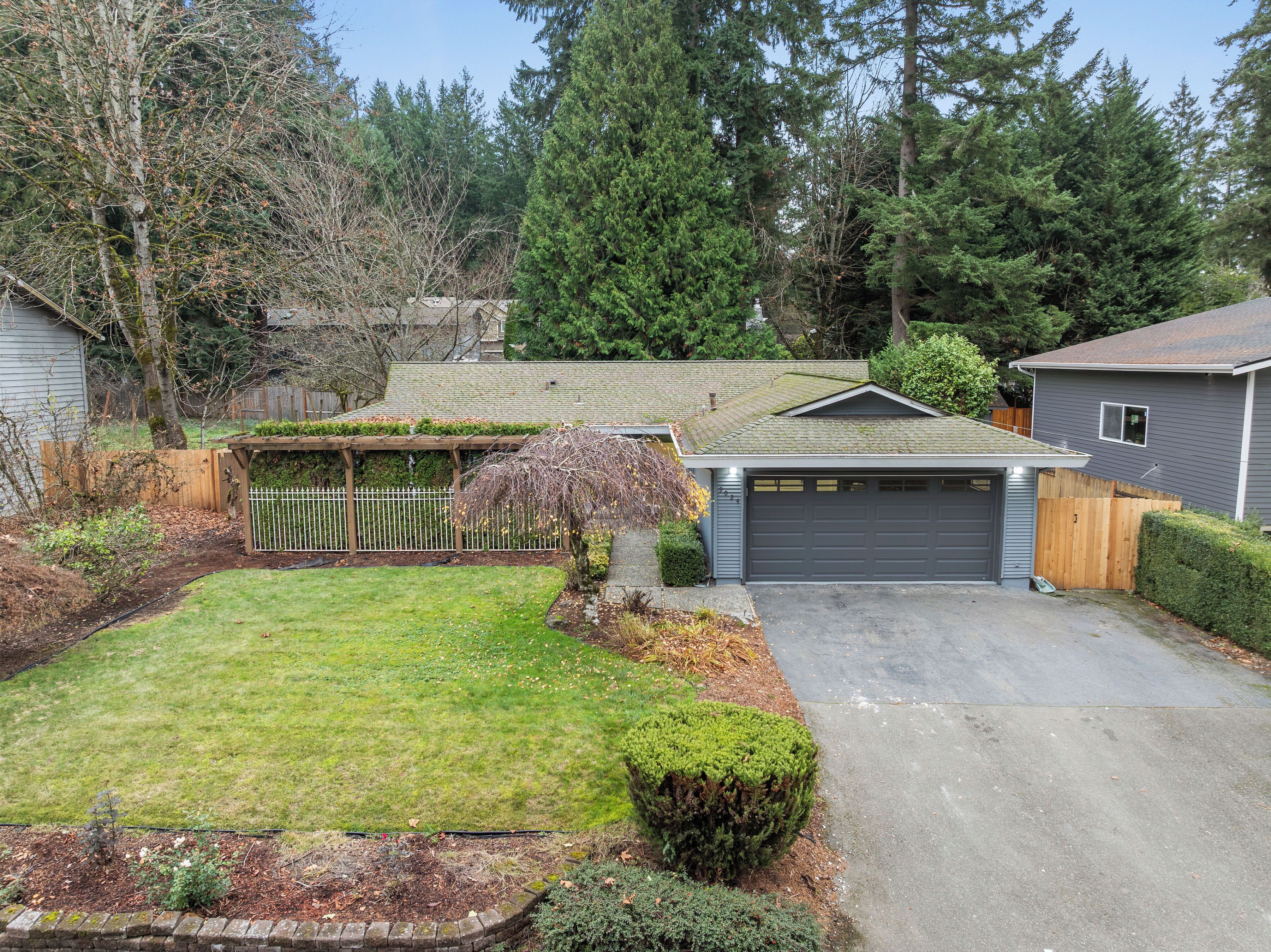A residential property with a well-maintained lawn, a garage, and a wooden fence.