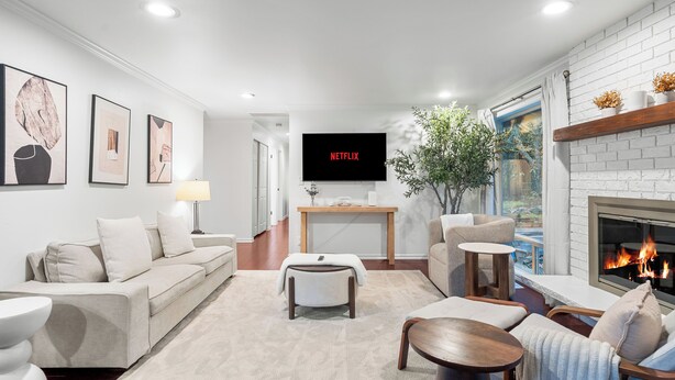 A modern living room with a fireplace, a flat-screen TV, and a comfortable seating area.