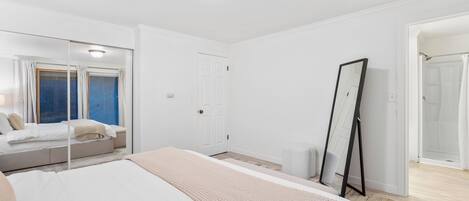 Un dormitorio con una cama grande, un espejo de tocador, un armario y una ventana con cortinas.