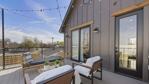 A deck with outdoor furniture, a large sliding glass door, and string lights.