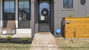 A modern house with a dark front door, a wooden bench outside, and a mailbox with the number 907.