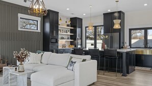 A modern kitchen with dark cabinetry, a white sofa, and pendant lighting.