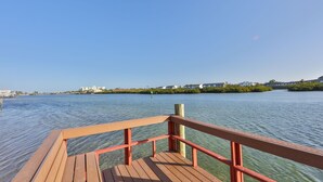 Un muelle de madera que se adentra en aguas tranquilas, con vistas despejadas a edificios lejanos y vegetación.