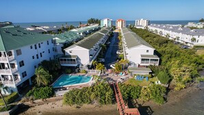 Un resort con varias edificaciones, una piscina central y una zona de playa.