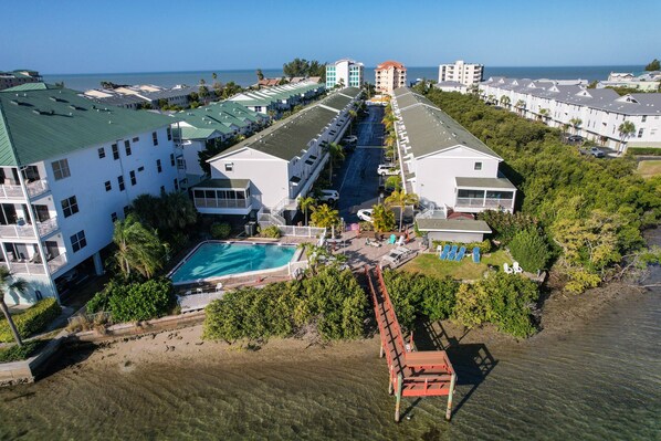 A resort with multiple buildings, a central swimming pool, and a beach area.