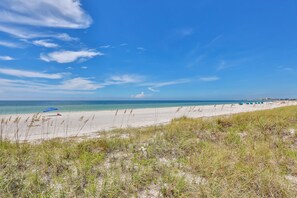 A beach with a clear sky, sandy shore, and a row of beach umbrellas.