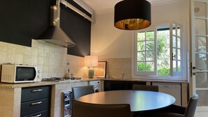 Una cocina moderna con microondas, estufa y lavamanos. Hay una mesa de comedor con sillas y una lámpara colgante.