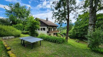 Une maison avec un court de tennis, située dans un jardin luxuriant.
