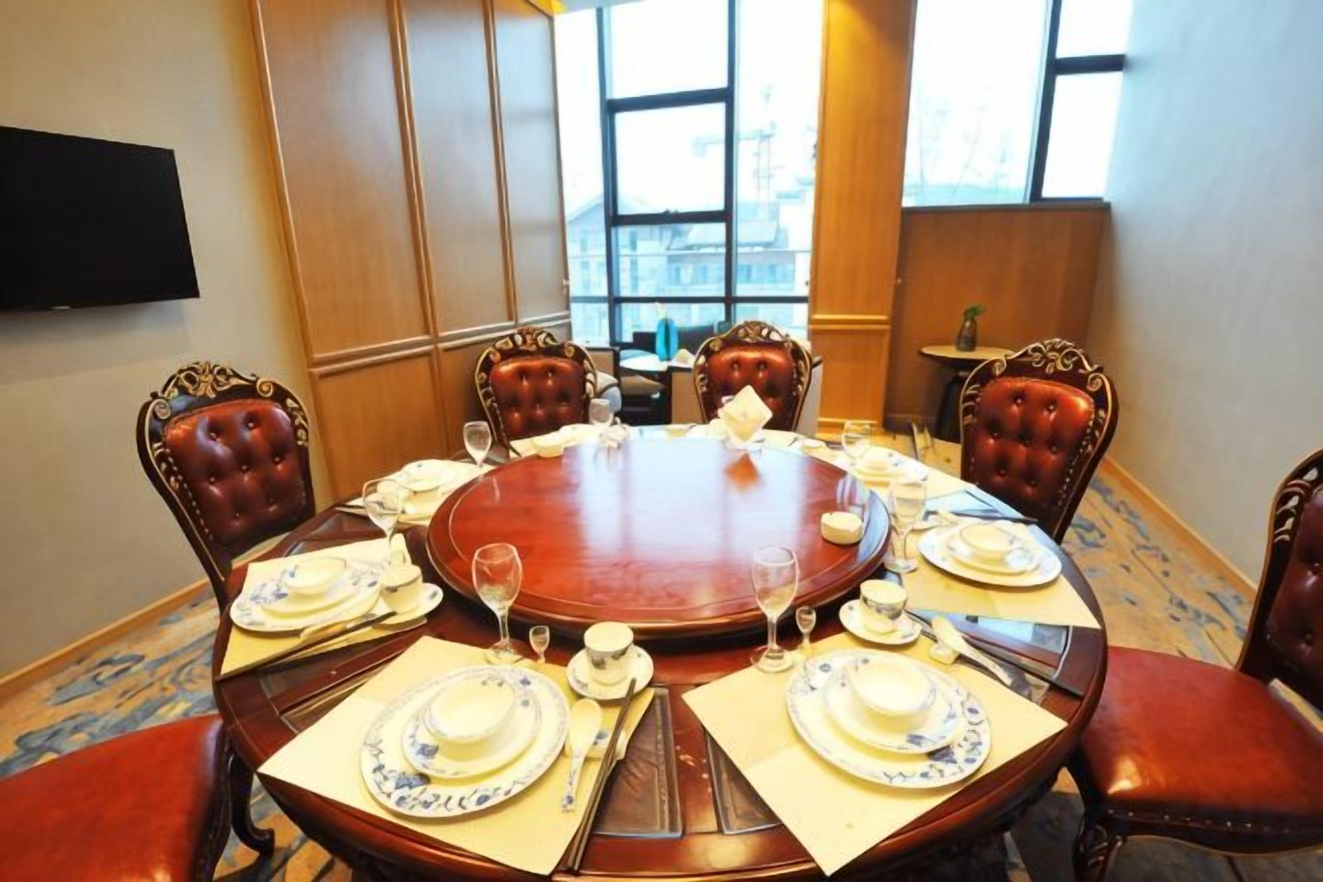 A conference room with a round table, six chairs, and a television mounted on the wall.