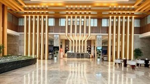 Un vestíbulo espacioso con una recepción central, techos altos y un diseño moderno.