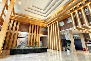 Un vestíbulo amplio con una exhibición central, techos altos y detalles de madera moderna.