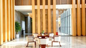 Un vestíbulo amplio con zona de comedor central, techos altos y paneles de madera verticales.