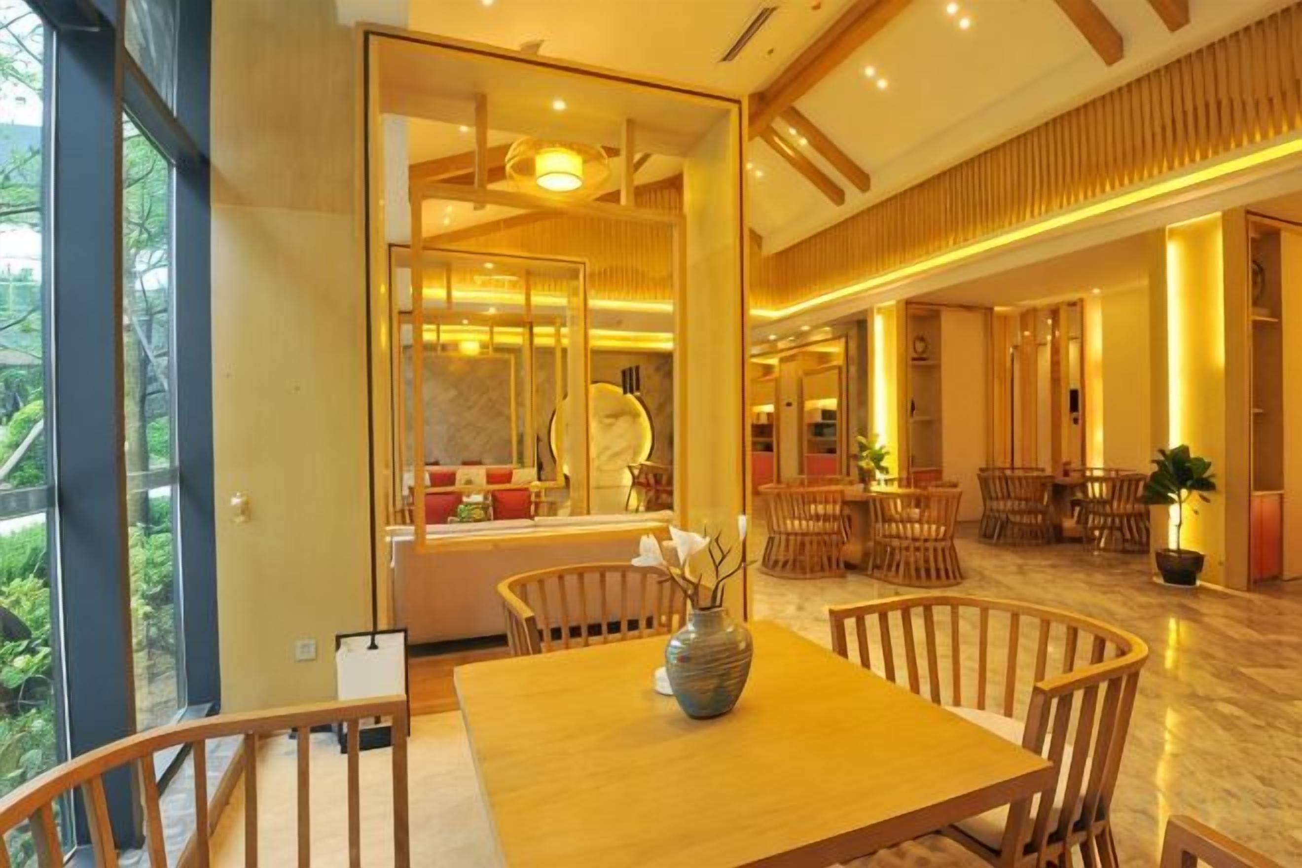 A modern interior with a wooden dining table, chairs, and a vase. There are multiple seating areas with tables and chairs.
