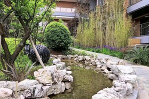 A landscaped garden with a pond, rocks, and various plants. - Xiyue Hotel (Qingzhen)
