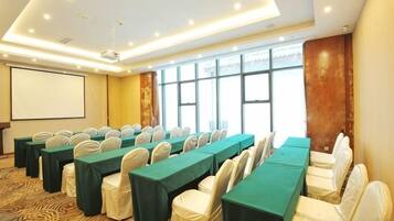 A conference room with long tables, chairs, a projector screen, and a large window.