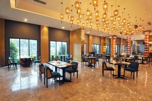 A spacious dining area with multiple tables and chairs, large windows, and hanging pendant lights. - Xiyue Hotel (Qingzhen)