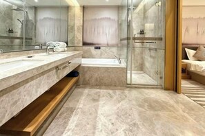 Une salle de bain moderne avec un comptoir en marbre, une baignoire et une cabine de douche en verre.