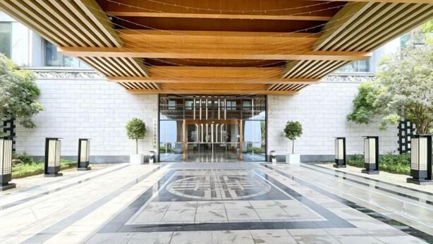 Una entrada de edificio moderna con piso estampado, techo de madera y puerta de vidrio.