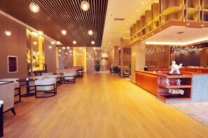 Un hall d’hôtel doté d’un plancher en bois, d’un espace salon, d’un comptoir d’accueil et d’un escalier.